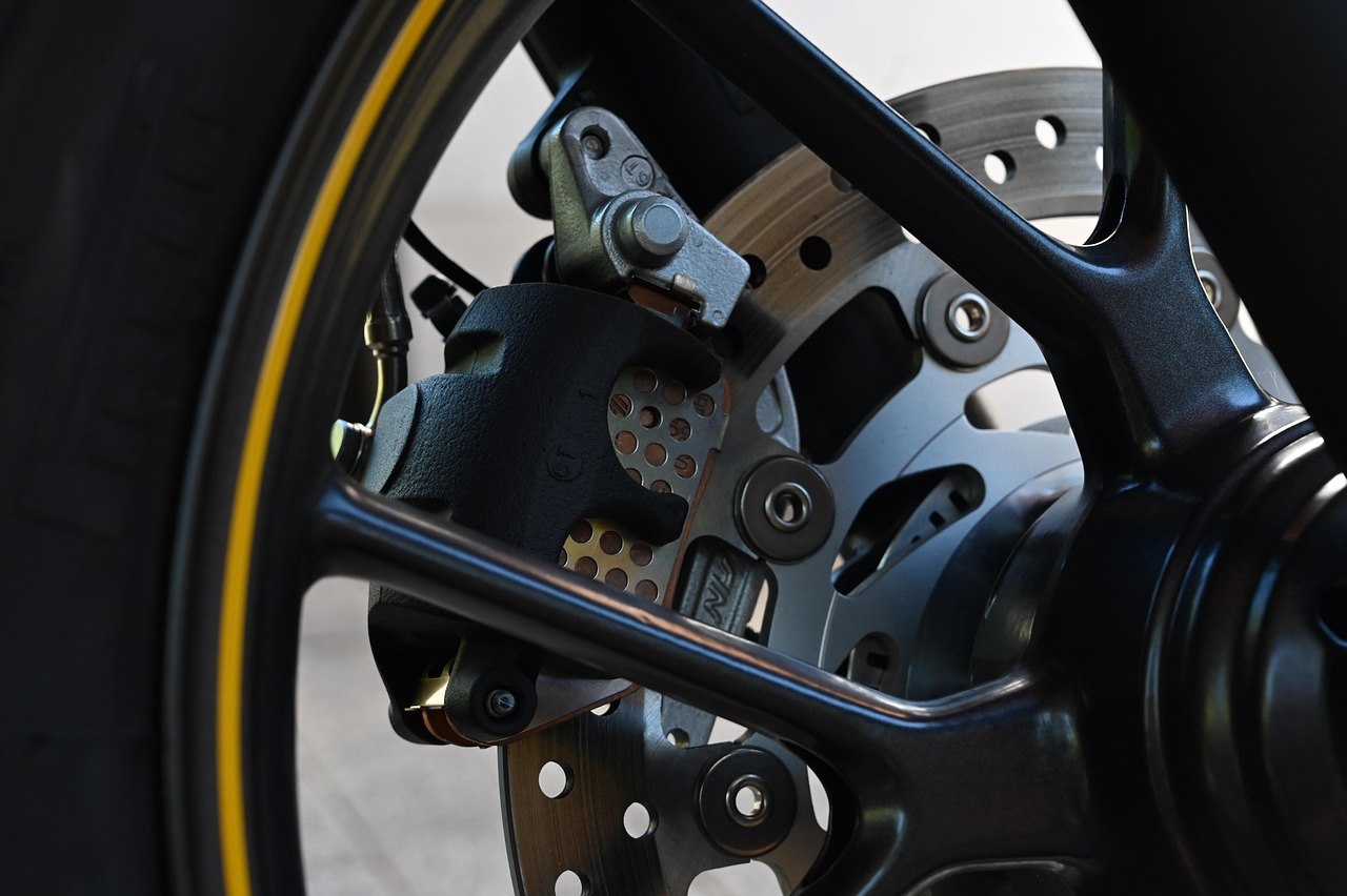 黒いホイールのスポーク越しに見た、穴あきのブレーキディスクと、ディスクを挟む黒いブレーキキャリパー
