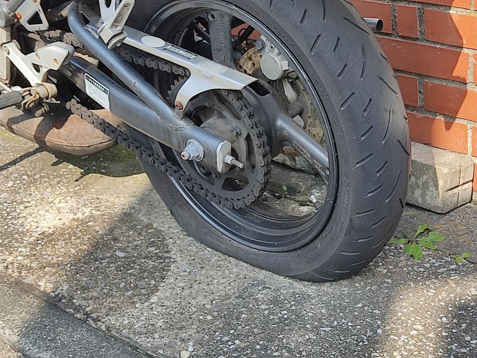 バイクの後輪に釘が刺さってパンクしたタイヤのクローズアップ